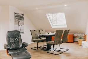 Un espace repas comprenant une table, des chaises et une lucarne.