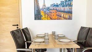 Uma sala de jantar com mesa de madeira, cadeiras pretas e um quadro com vista para a cidade.