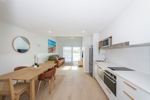 A modern kitchen with white cabinetry, a built-in microwave, and a stainless steel refrigerator.