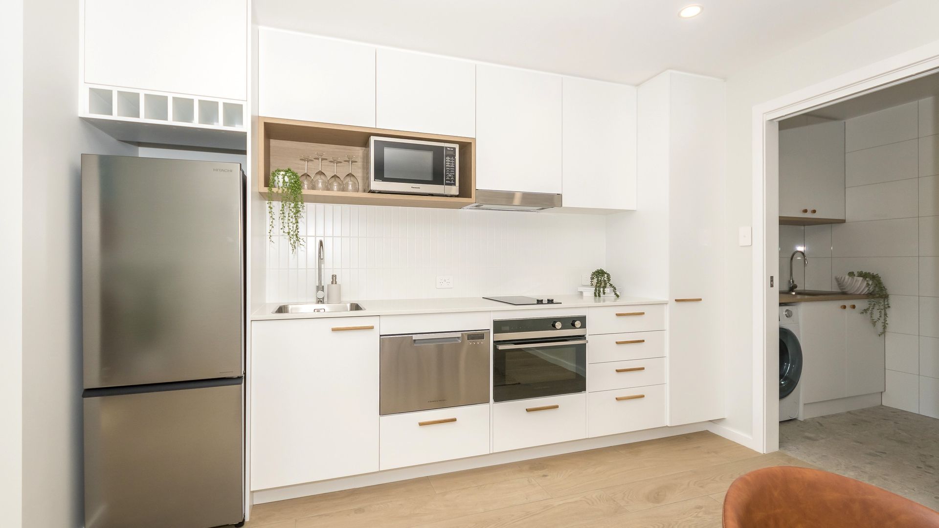 A modern kitchen with stainless steel appliances, white cabinetry, and a microwave above the countertop.