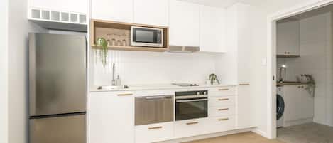A modern kitchen with stainless steel appliances, white cabinetry, and a microwave above the countertop.