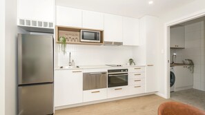 A modern kitchen with stainless steel appliances, white cabinetry, and a microwave above the countertop. - Marina 14, Harrington (Harrington)