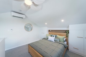 A bedroom with a bed, a round mirror, a ceiling fan, and built-in wardrobes.