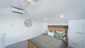 A bedroom with a bed, a round mirror, a wardrobe, and an air conditioning unit. - Marina 14, Harrington (Harrington)