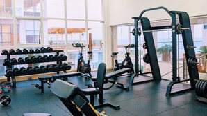 Un gimnasio con equipo de levantamiento de pesas, mancuernas y máquinas de cardio.