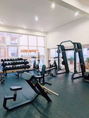 Une salle de sport équipée de matériel de musculation, d’haltères et d’appareils de cardio.