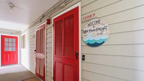 A hallway with red doors, a welcome sign, and a doormat. - "Dune Delight" At Sea Mystic (North Myrtle Beach)