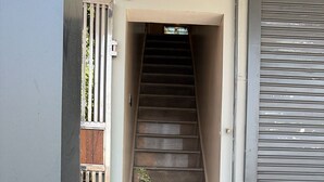 A staircase leading to an entrance, a potted plant, and a closed garage door. - Moon Stay Panipat (Panipat)