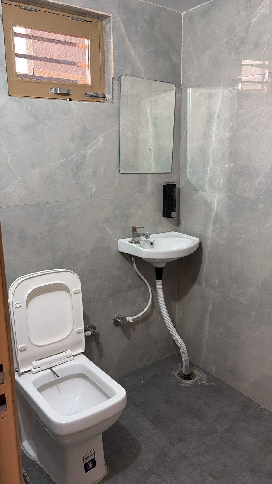 A bathroom with a toilet, sink, and mirror.