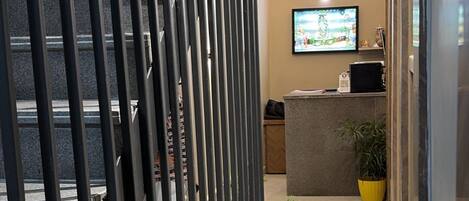 A reception area with a reception desk, a television screen, and a staircase with metal railings.
