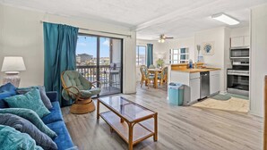 Una sala moderna con un sofá, una mesa de centro de vidrio y una silla de mimbre.