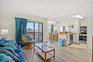 Ein modernes Wohnzimmer mit einer Couch, einem Couchtisch mit Glasplatte und einem Korbstuhl.