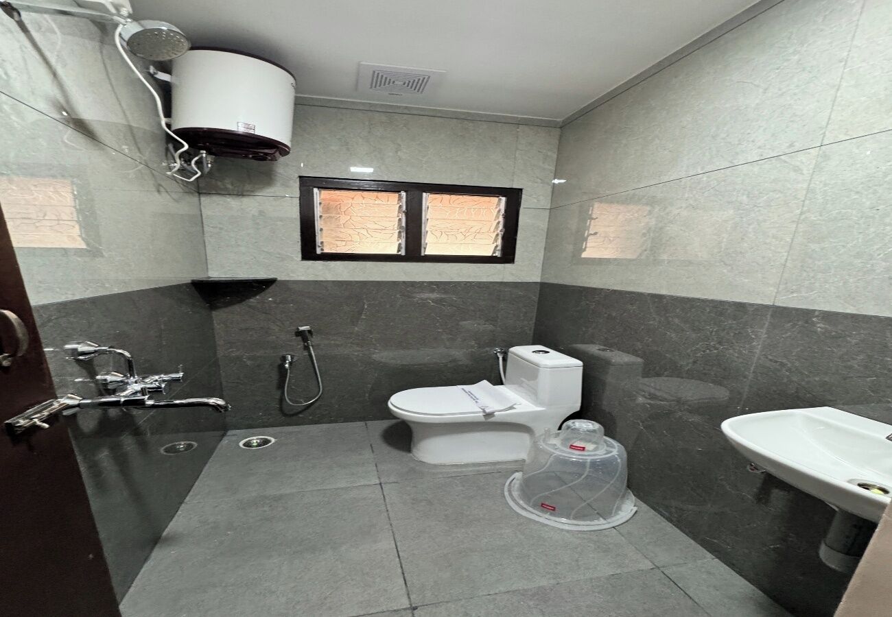 Une salle de bain équipée de toilettes, d’un bidet, d’un lavabo et d’un chauffe-eau fixé au mur.