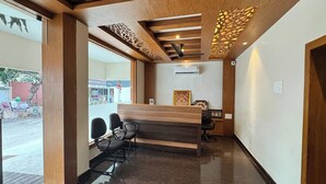 Un mostrador de recepción con detalles de madera, sillas negras y un dise ño de techo con motivos.