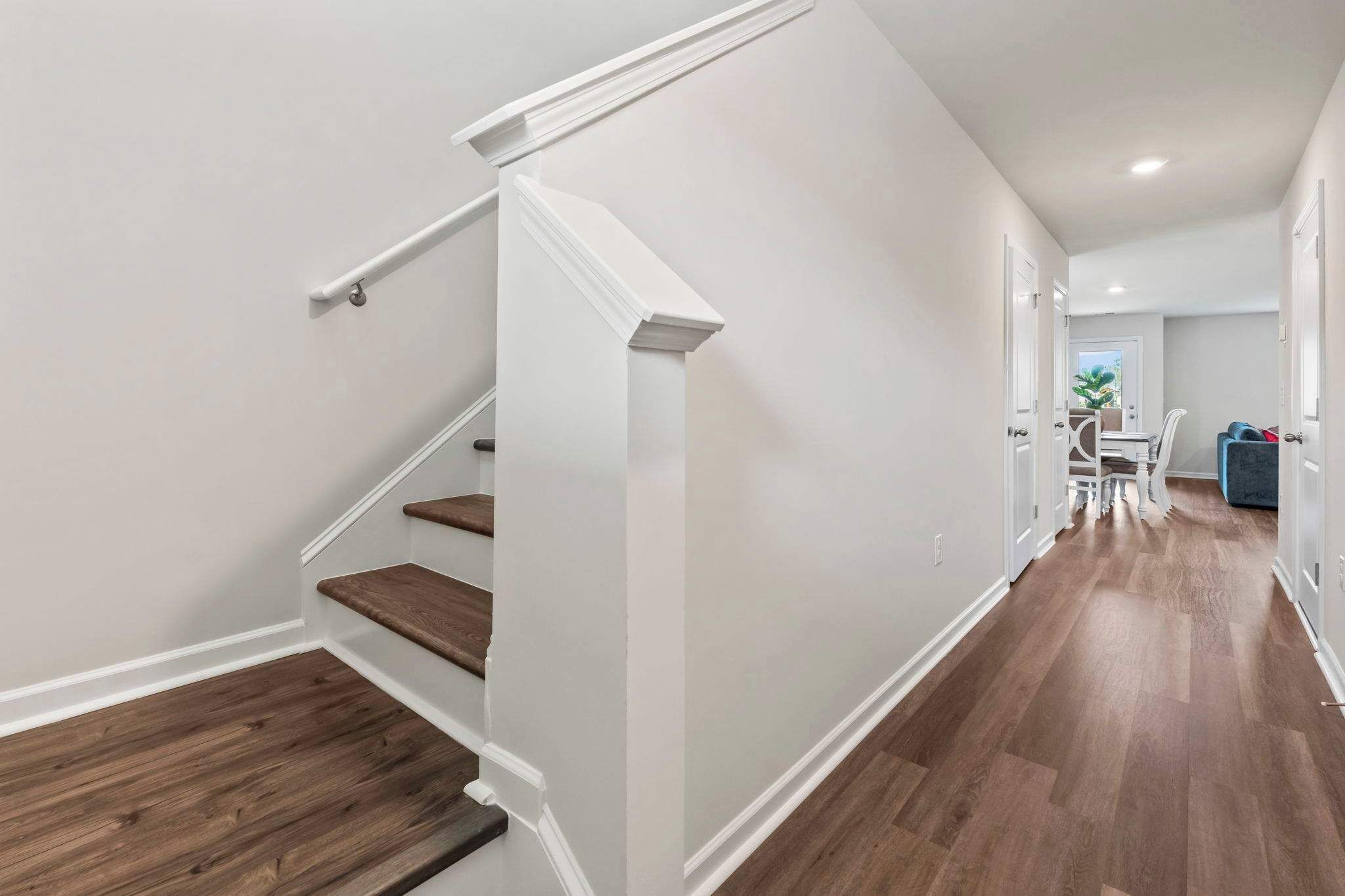 A modern interior with a staircase, wooden flooring, and a dining area with a table and chairs.