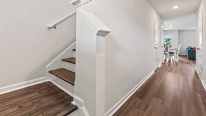 Een modern interieur met een trap, houten vloeren en een eethoek met een tafel en stoelen.