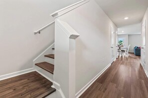 Ein modernes Interieur mit einer Treppe, Holzboden und einer Essecke mit Tisch und Stühlen.