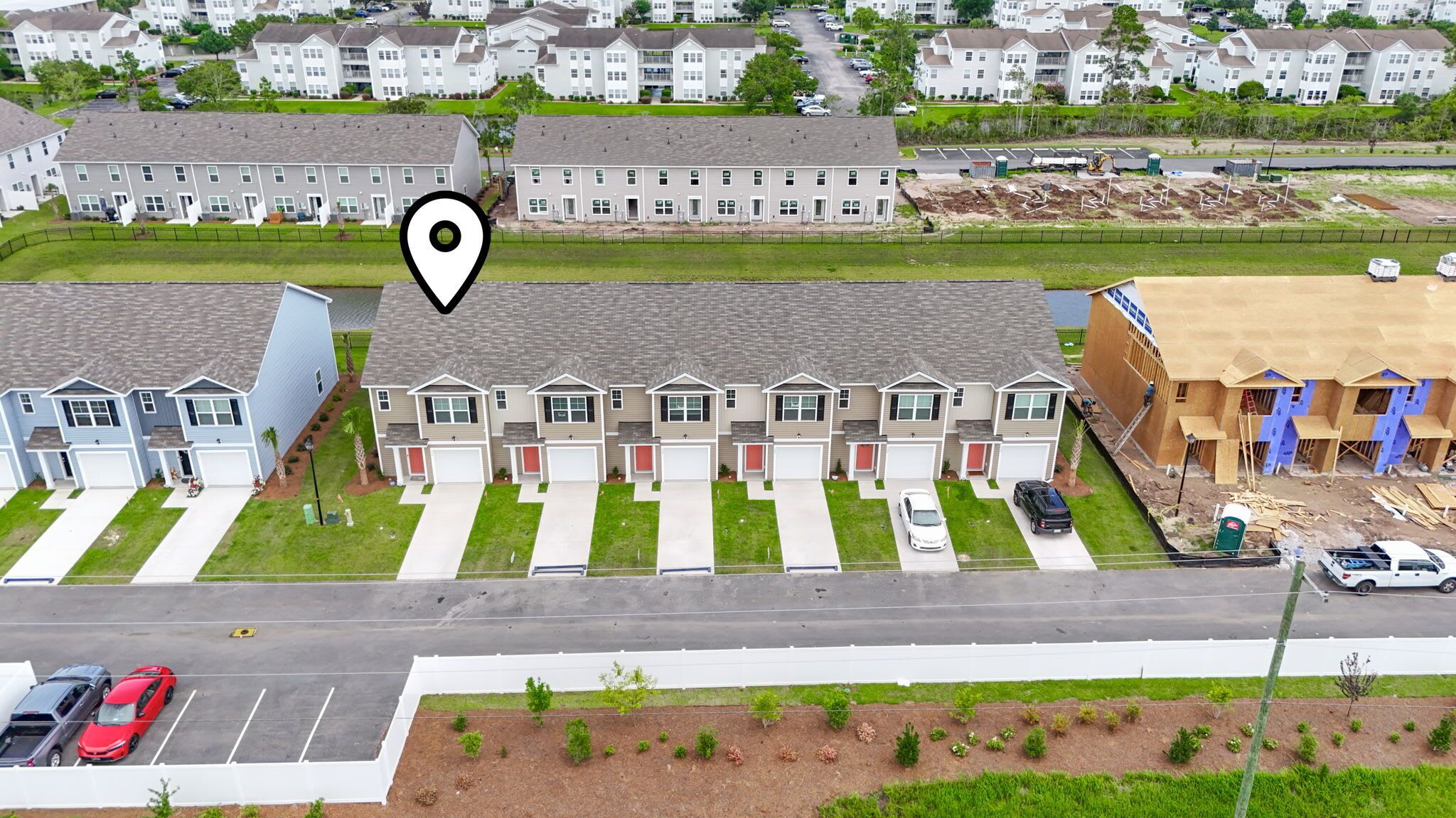 A residential area with a row of townhouses, a parking lot, and a construction site.
