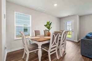 A dining area with a wooden table, white chairs, and a potted plant. - "Surfside Beach Oasis" (Myrtle Beach)