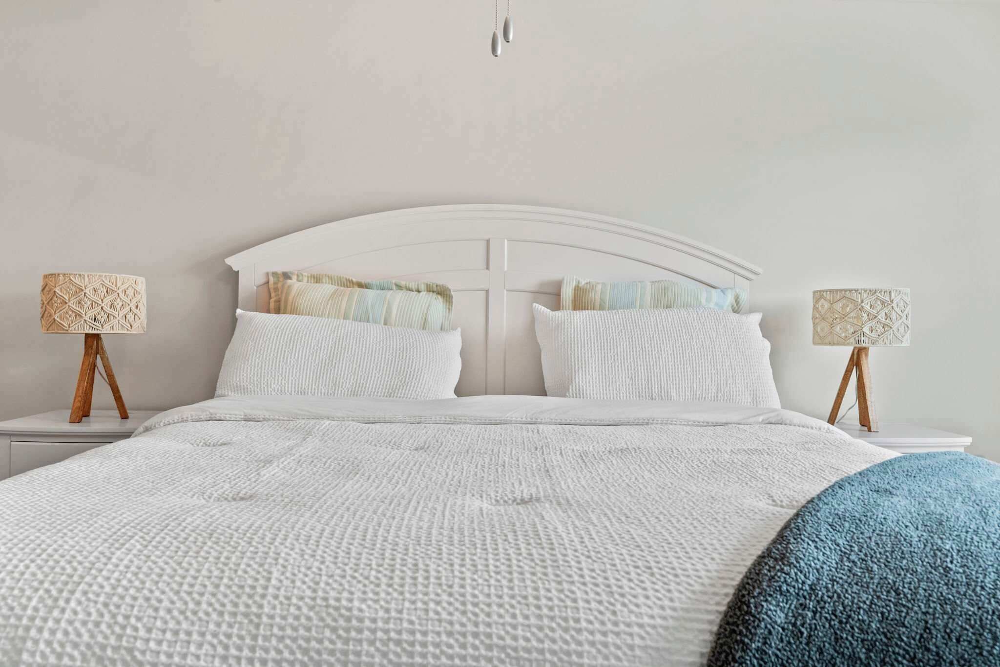 A bed with a white headboard, two bedside tables with lamps, and a blue throw blanket.