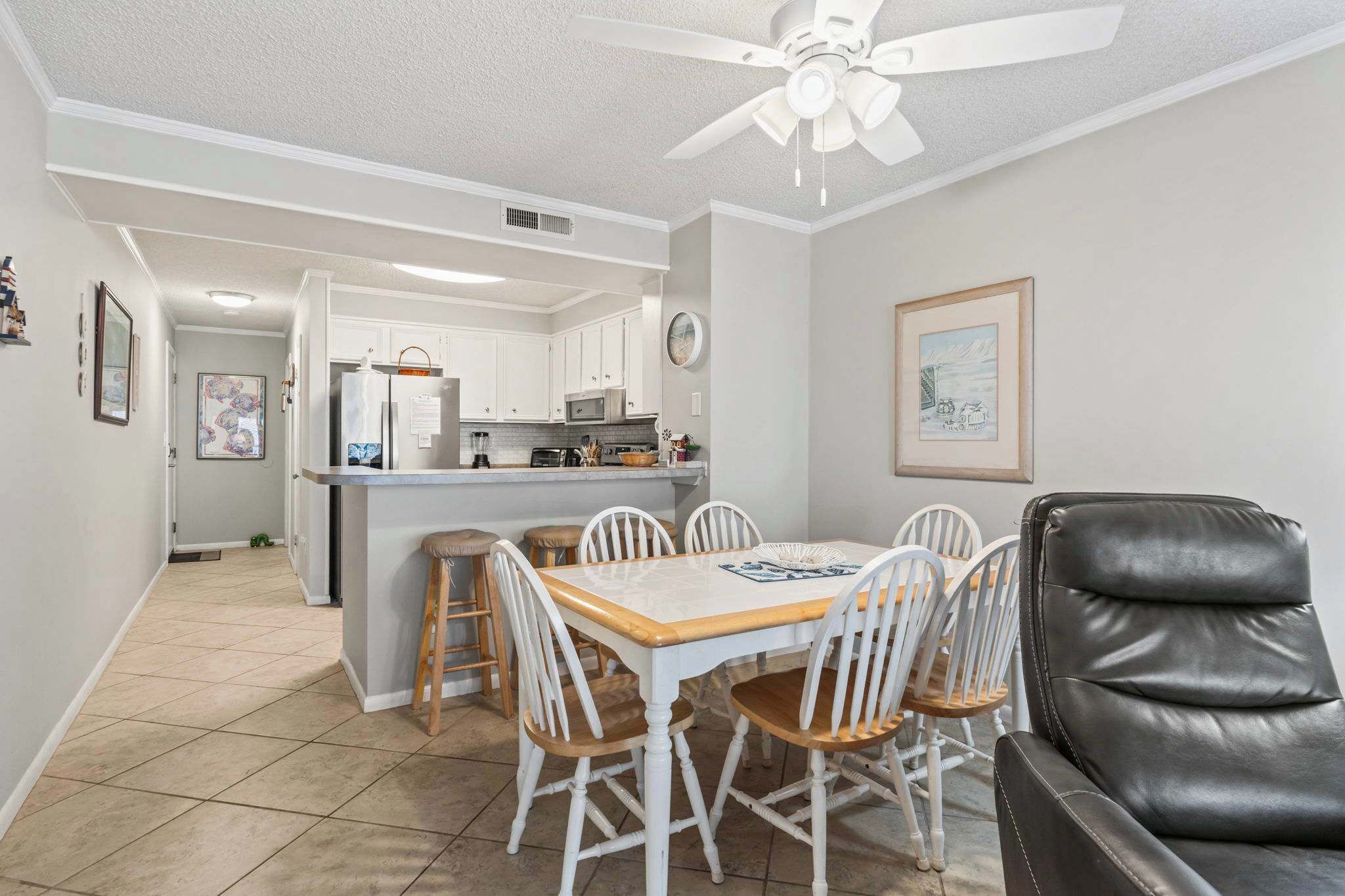 A compact kitchen with white cabinets, a microwave, and a dining area with a wooden table and white chairs.