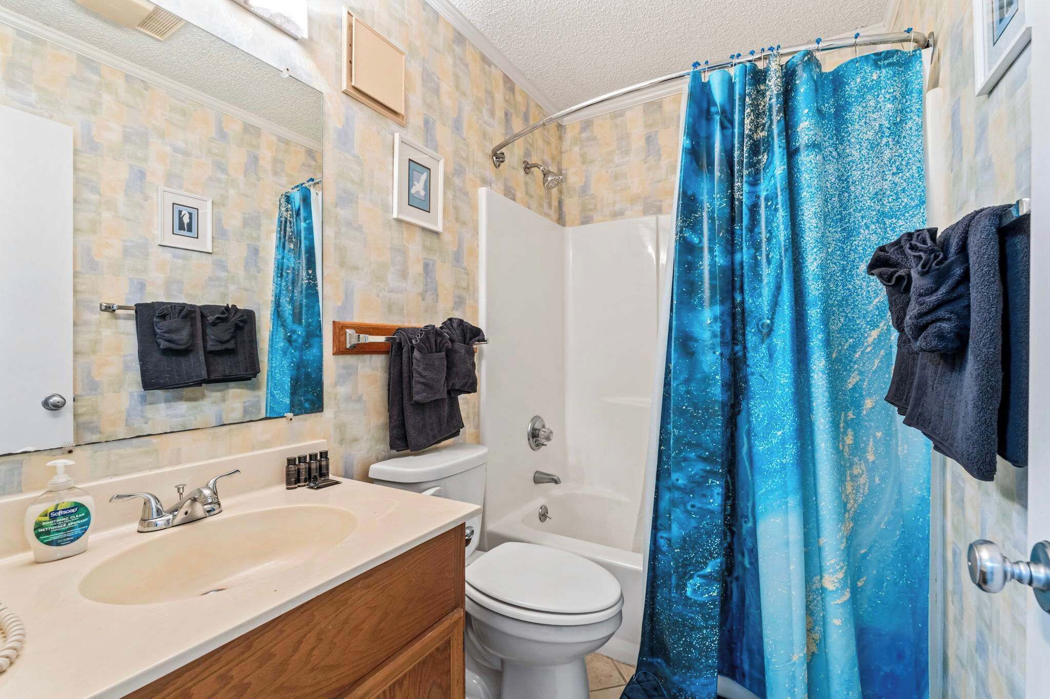 A bathroom with a shower curtain, a sink, a toilet, and a mirror.