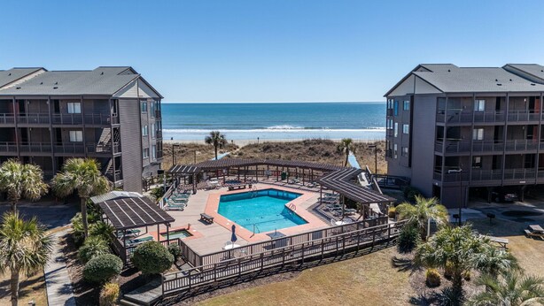 A pool area with a view of the ocean, surrounded by buildings with balconies. - Orange Crush at Tilghman (North Myrtle Beach)