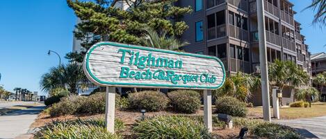 Segnale per Tighman Beach & Racquet Club, con un edificio a più piani sullo sfondo.