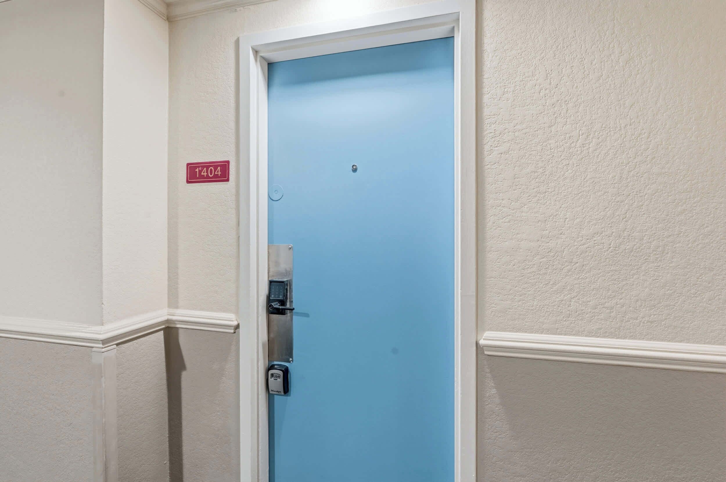 Una puerta azul con teclado numérico, marco blanco y pared texturizada de color blanco con el símbolo de número.