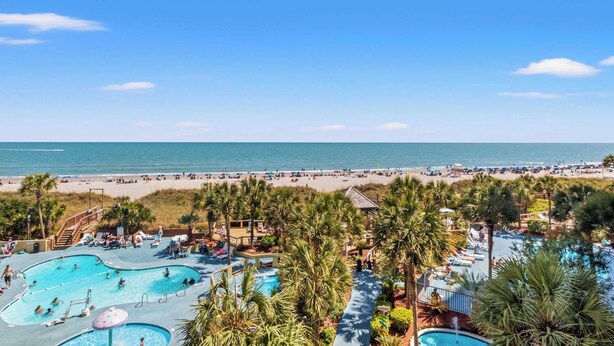 Ein Resort mit mehreren Schwimmbecken, einem Strand und Palmen.