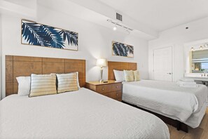 Une chambre d’hôtel avec deux lits, une tête de lit en bois, une table de chevet, une lampe et des œuvres d’art accrochées aux murs.