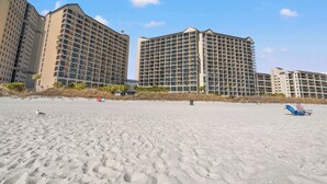 Ein Strandhotel mit mehreren Hochhäusern, Sandstrand und blauem Himmel.