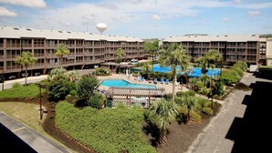 A hotel with a swimming pool, palm trees, and a view of the surrounding area. - "The Pearl of Tilghman" (North Myrtle Beach)