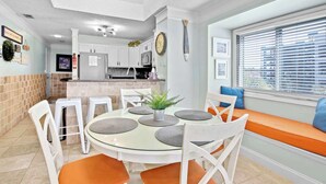 A dining area with a round glass table, white chairs, and orange cushions. - "The Pearl of Tilghman" (North Myrtle Beach)