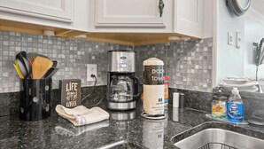 A kitchen with white cabinets, a coffee maker, a paper towel dispenser, and dish soap. - "The Pearl of Tilghman" (North Myrtle Beach)