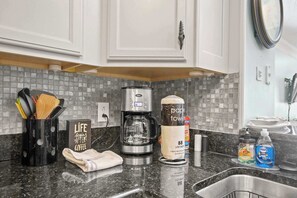 A kitchen with white cabinets, a coffee maker, a paper towel dispenser, and dish soap. - "The Pearl of Tilghman" (North Myrtle Beach)