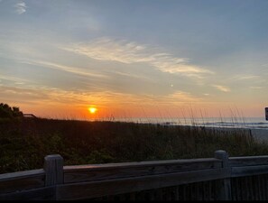 Ein Sonnenuntergang über einem Strand mit einer Holzpromenade.