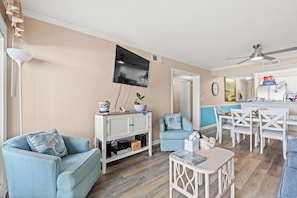 A living room with a TV, two sofas, a coffee table, and a dining area with a table and chairs. - Tequila at Tilghman Resort (North Myrtle Beach)