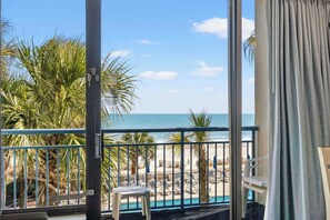 A balcony with a view of the beach and ocean, a pool, and a chair. - "The Grand Coral" located coral beach (Myrtle Beach)