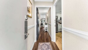 A hallway with a wooden floor, white walls, and a patterned rug. - "Dreams By The Sea" at dunes village (Myrtle Beach)