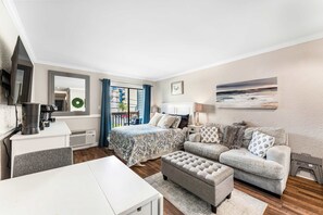 Ein modernes Schlafzimmer mit Bett, Sofa, Kaffeemaschine und Fernseher.