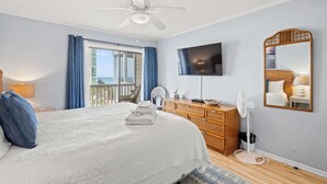 A hotel room with a bed, a television, a ceiling fan, a dresser, and a view of the outdoors. - "Soul Soother" at Tilghman (North Myrtle Beach)