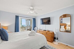 A hotel room with a bed, a television, a ceiling fan, a dresser, and a view of the outdoors. - "Soul Soother" at Tilghman (North Myrtle Beach)