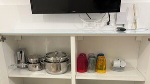 Eine Küche mit Fernseher über der Arbeitsplatte, Edelstahlkochgeschirr und Glasvorratsgläsern.