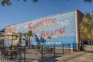 Une fresque représentant « Surfside Beach », avec des tables et des chaises à l’extérieur et des palmiers.