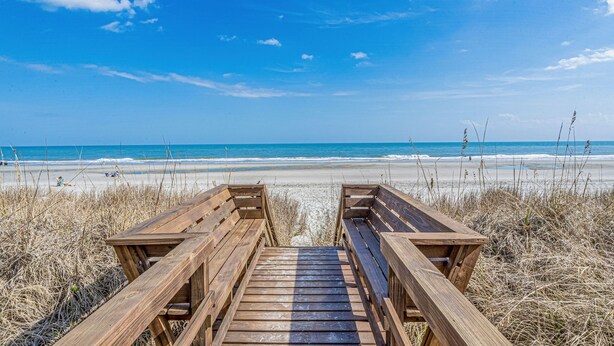 A wooden boardwalk leading to a beach with clear skies. - Coastal Cottage- 3 Bedroom (Surfside Beach)