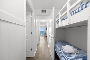 A narrow hallway with bunk beds, a door, and a view to a balcony. - B303 Myrtle Beach Resort (Myrtle Beach)