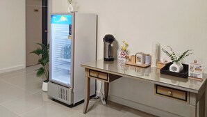 A hotel room with a minibar, a coffee maker, a plant, and a desk with a computer monitor. - The Olive House Hotel (Khon Kaen)