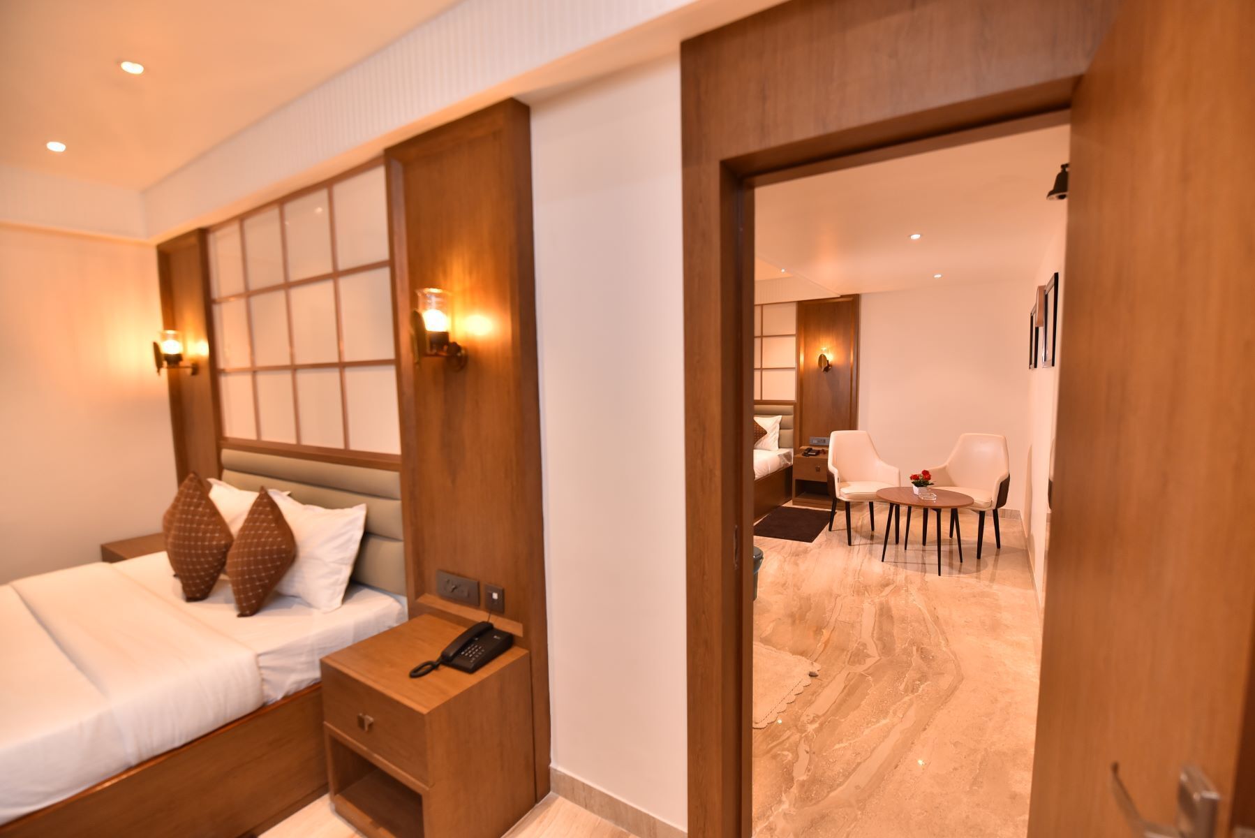 A hotel room with a bed, bedside table, and a desk with chairs.