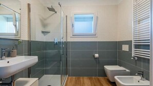 Ein Badezimmer mit Duschkabine, Waschbecken, Toilette und Bidet.